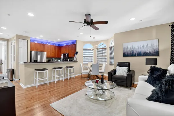 a living room with furniture kitchen view and a wooden floor