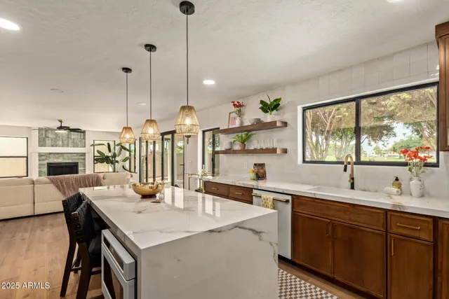 a kitchen with stainless steel appliances kitchen island granite countertop a refrigerator a oven a stove and a dining table with wooden floor