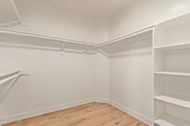 an empty room with wooden floor ceiling fan and windows