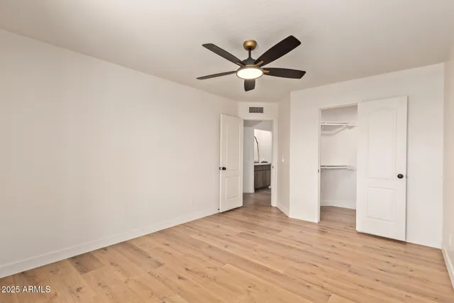 an empty room with wooden floor ceiling fan and windows