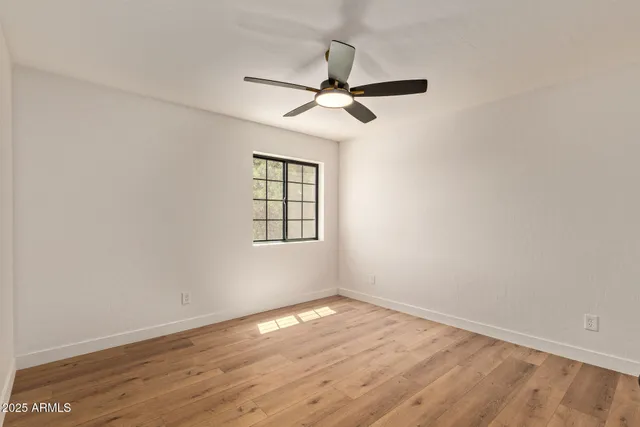 an empty room with wooden floor and ceiling fan
