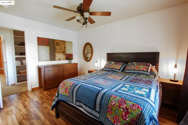 a bedroom with a bed a dresser with wooden floor