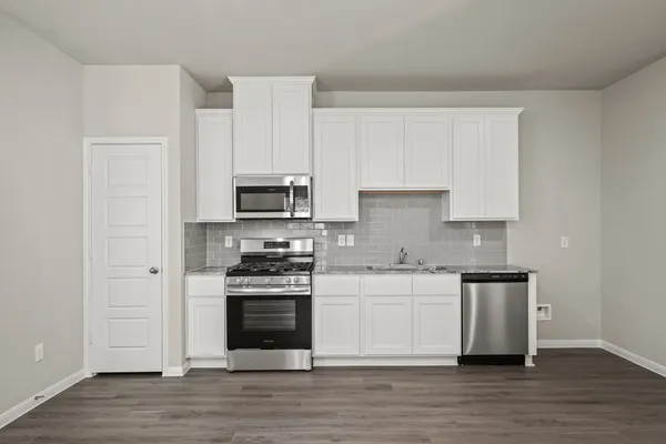 a kitchen with stainless steel appliances granite countertop a stove a sink and a microwave