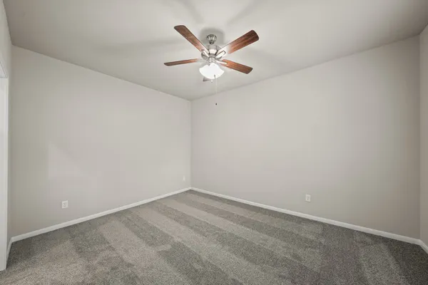 an empty room with window and ceiling fan