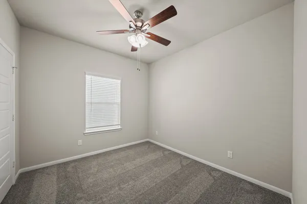 an empty room with a chandelier fan and windows