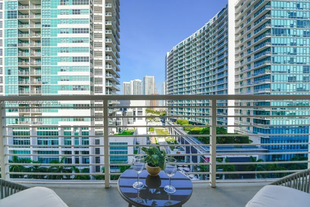 a balcony with table and chairs and potted plants