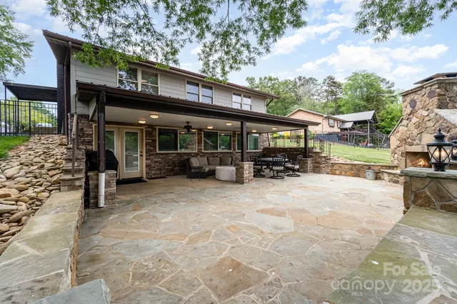 a view of a patio with table and chairs under an umbrella with large trees