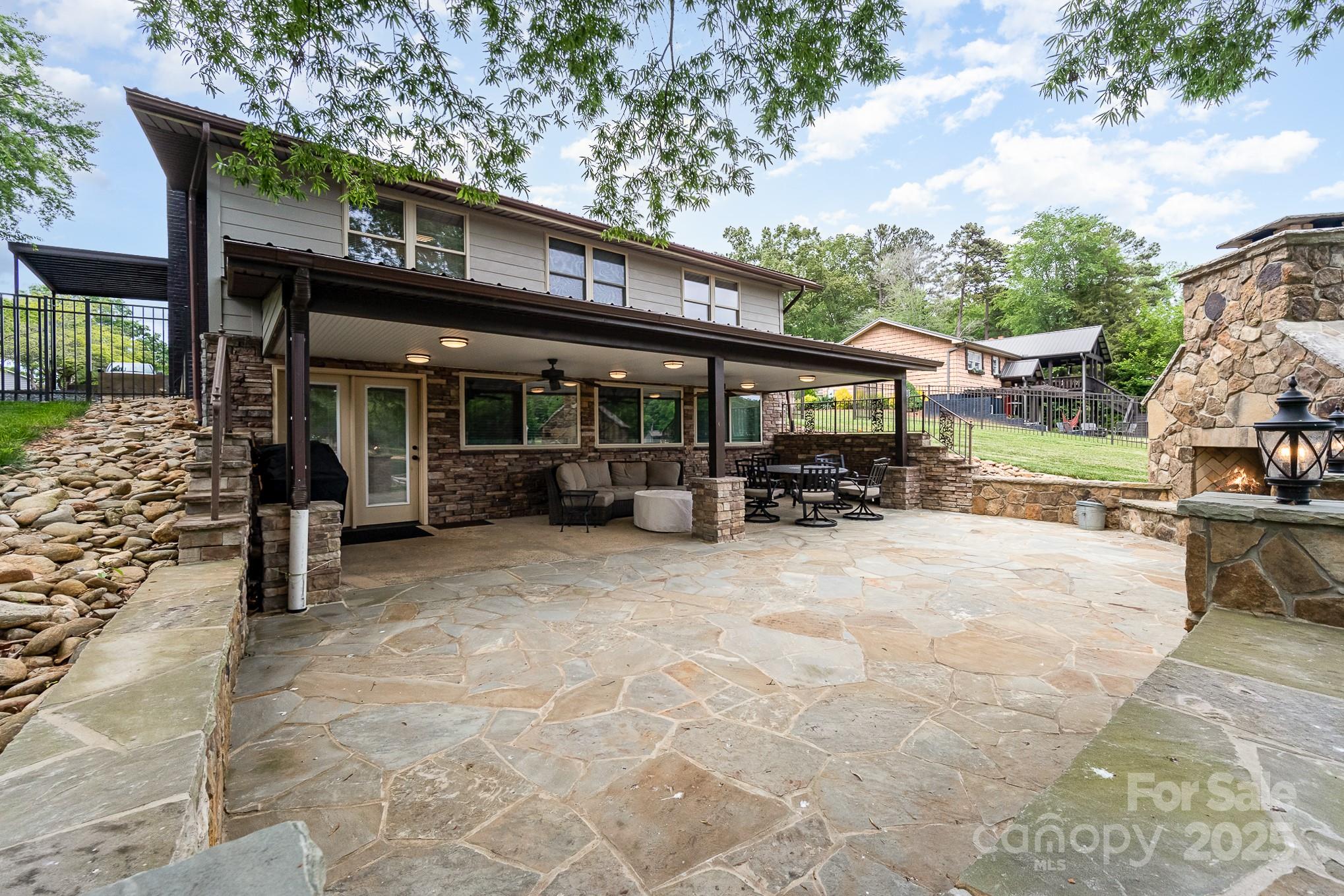 a view of a patio with table and chairs under an umbrella with large trees