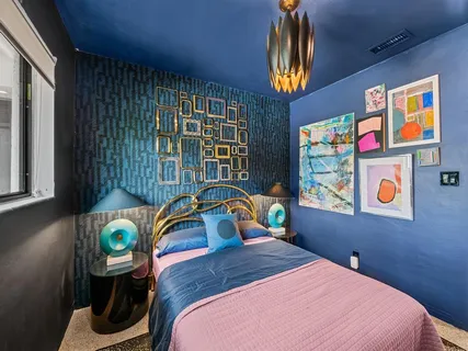 a bedroom with a bed a dresser and next to a window