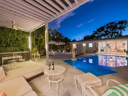 a view of swimming pool with outdoor seating and trees in the background