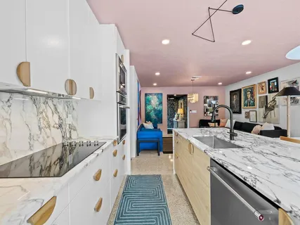 a large white kitchen with a sink and a stove top oven with wooden floor