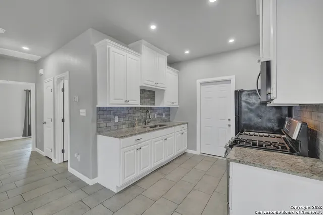 a kitchen that has a lot of cabinets in it and wooden floors