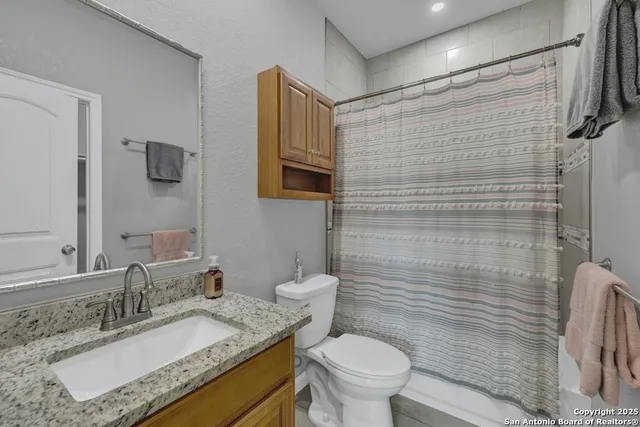 a bathroom with a granite countertop sink toilet and shower