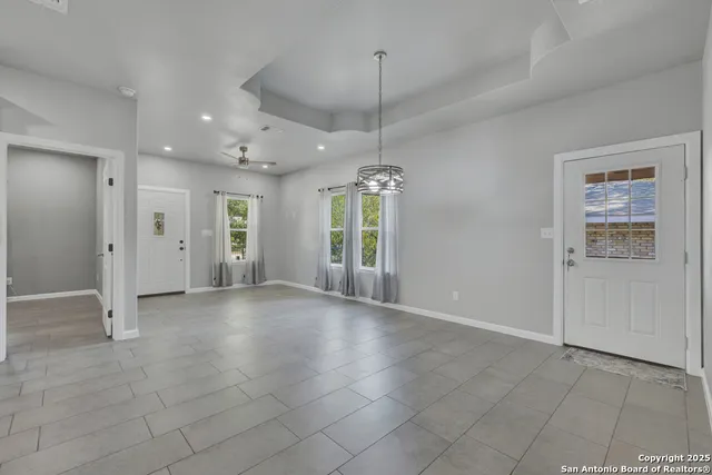 a view of an empty room with window and chandelier fan