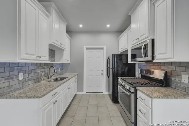 a kitchen with granite countertop a sink stove and refrigerator