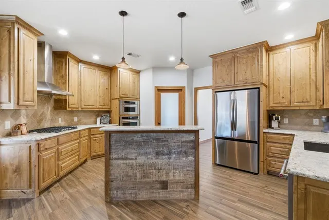 a large kitchen with granite countertop a stove a sink dishwasher a refrigerator and wooden floor