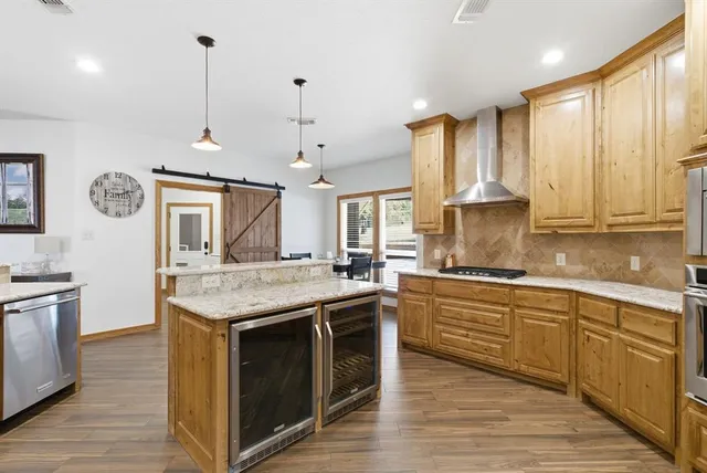 a kitchen with stainless steel appliances granite countertop a stove a sink dishwasher a refrigerator and a oven with wooden floor