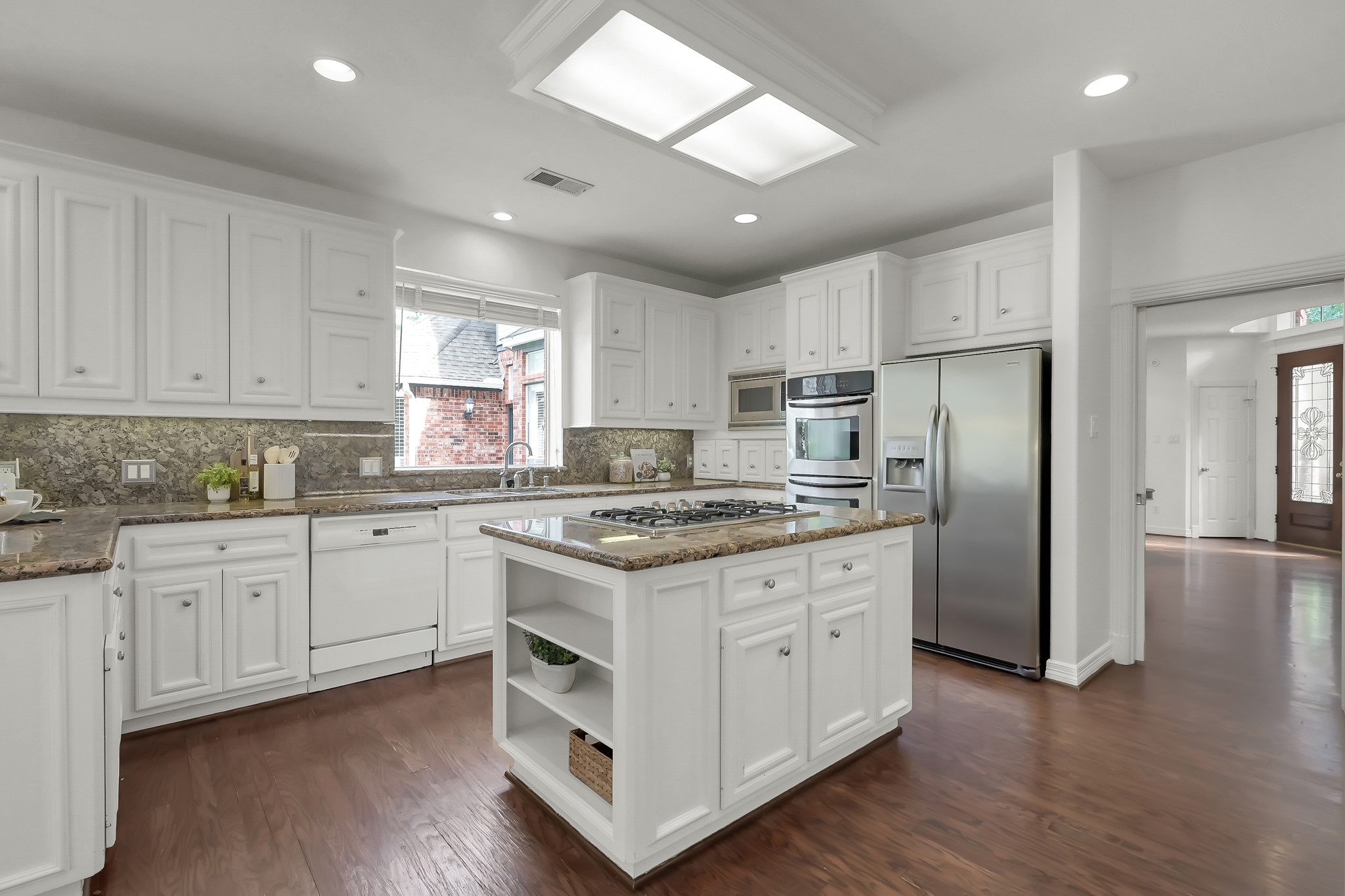 16403 Agusta Court Spring, TX 77379 - Photo 13 of 36 a kitchen with stainless steel appliances granite countertop a stove a sink dishwasher a refrigerator and white cabinets with wooden floor