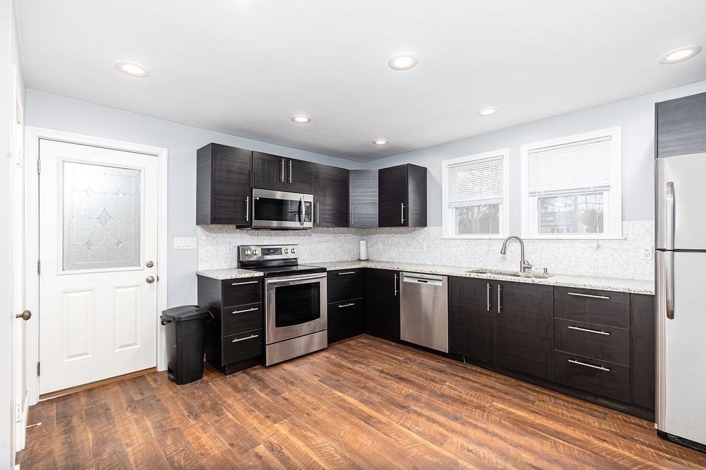 363 Concord Road Billerica, MA 01821 - Photo 9 of 42 a kitchen with stainless steel appliances granite countertop a stove top oven a sink dishwasher a refrigerator and a microwave oven with wooden floor