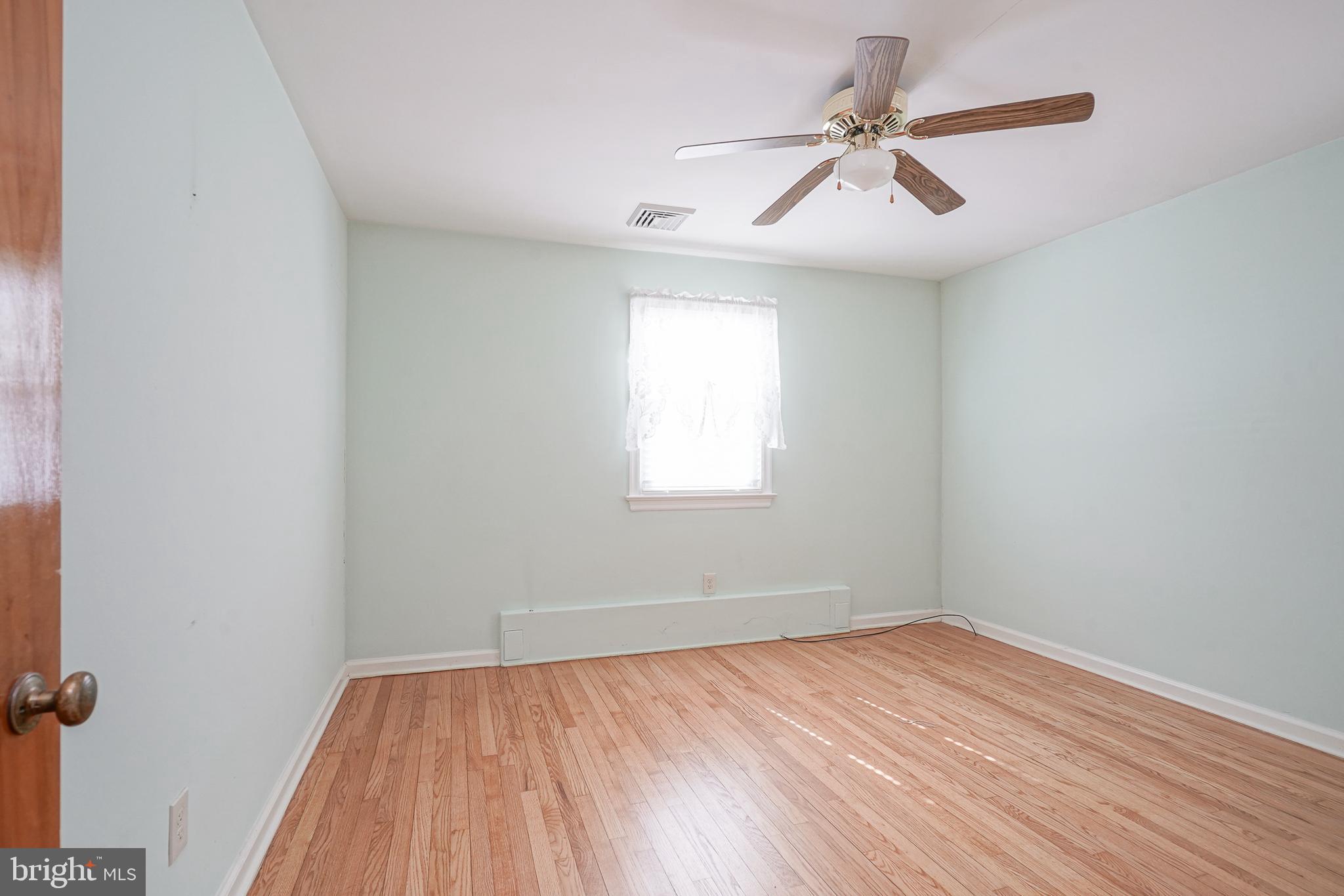 227 Harmony Road Gibbstown, NJ 08027 - Photo 20 of 29 an empty room with wooden floor ceiling fan and windows