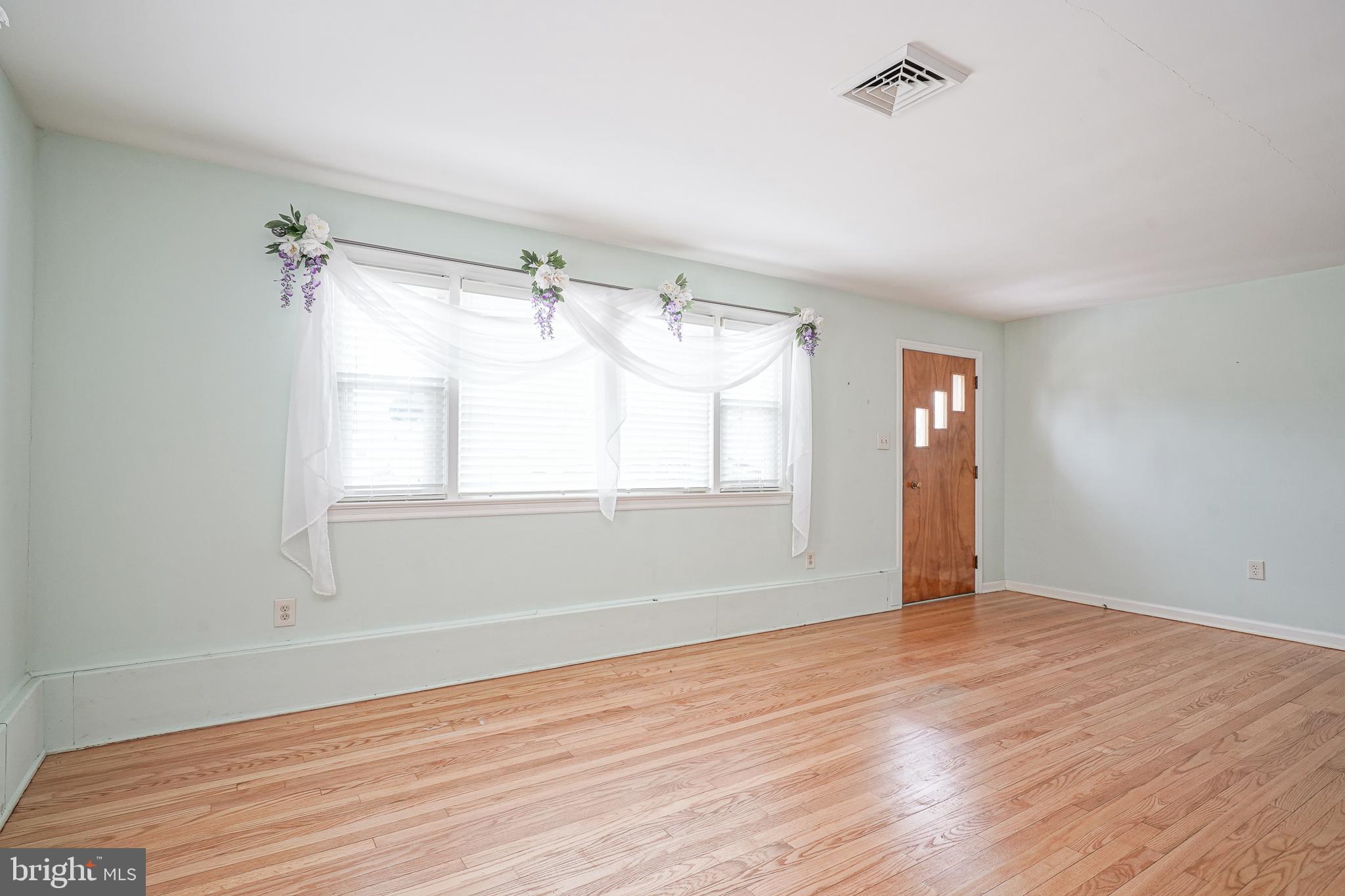 227 Harmony Road Gibbstown, NJ 08027 - Photo 5 of 29 a view of an empty room with wooden floor and a window