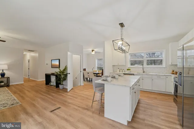 a kitchen with stainless steel appliances a sink a stove a oven a dining table and chairs