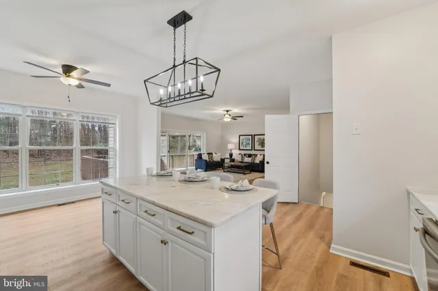 a kitchen with stainless steel appliances granite countertop a dining table chairs refrigerator and microwave