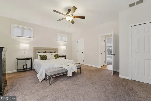 a bedroom with a large bed and a chandelier fan