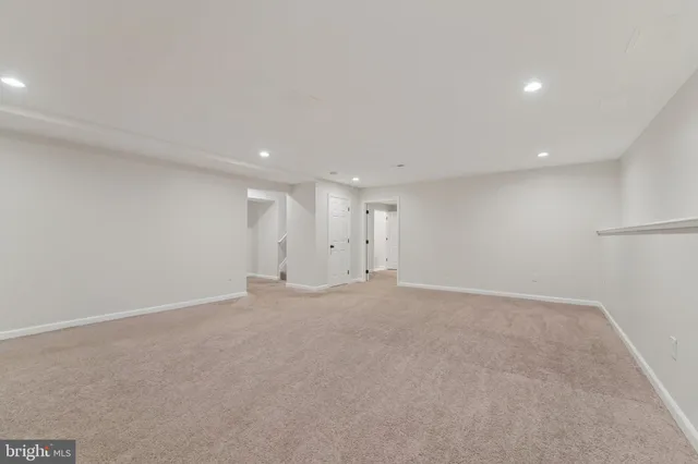 an empty room with a chandelier fan and windows