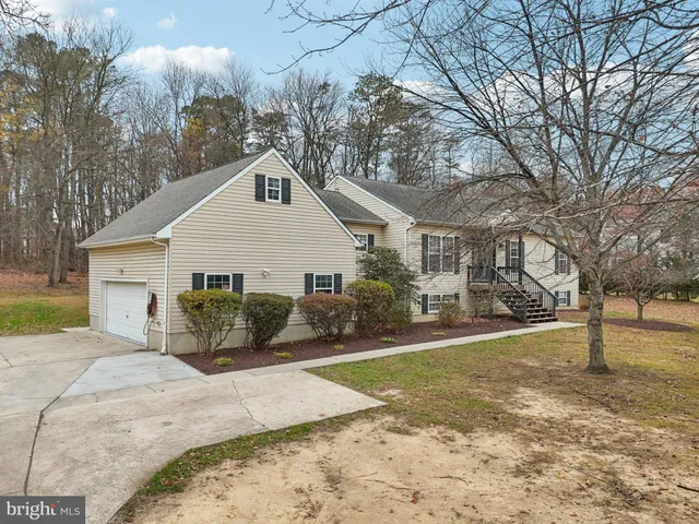 a view of a white house next to a yard with big trees