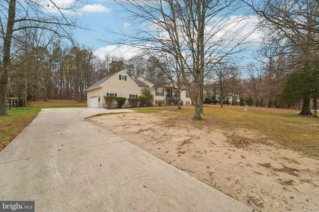 a view of a white house with a yard and large trees