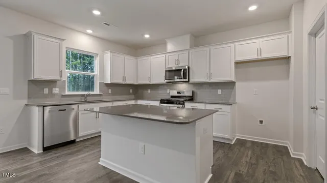 a kitchen with kitchen island granite countertop a sink cabinets and wooden floor
