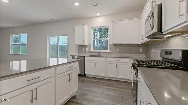 a kitchen with cabinets appliances a sink and a window