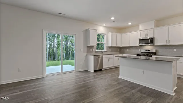 a kitchen with stainless steel appliances granite countertop a refrigerator a sink a stove a microwave and cabinets