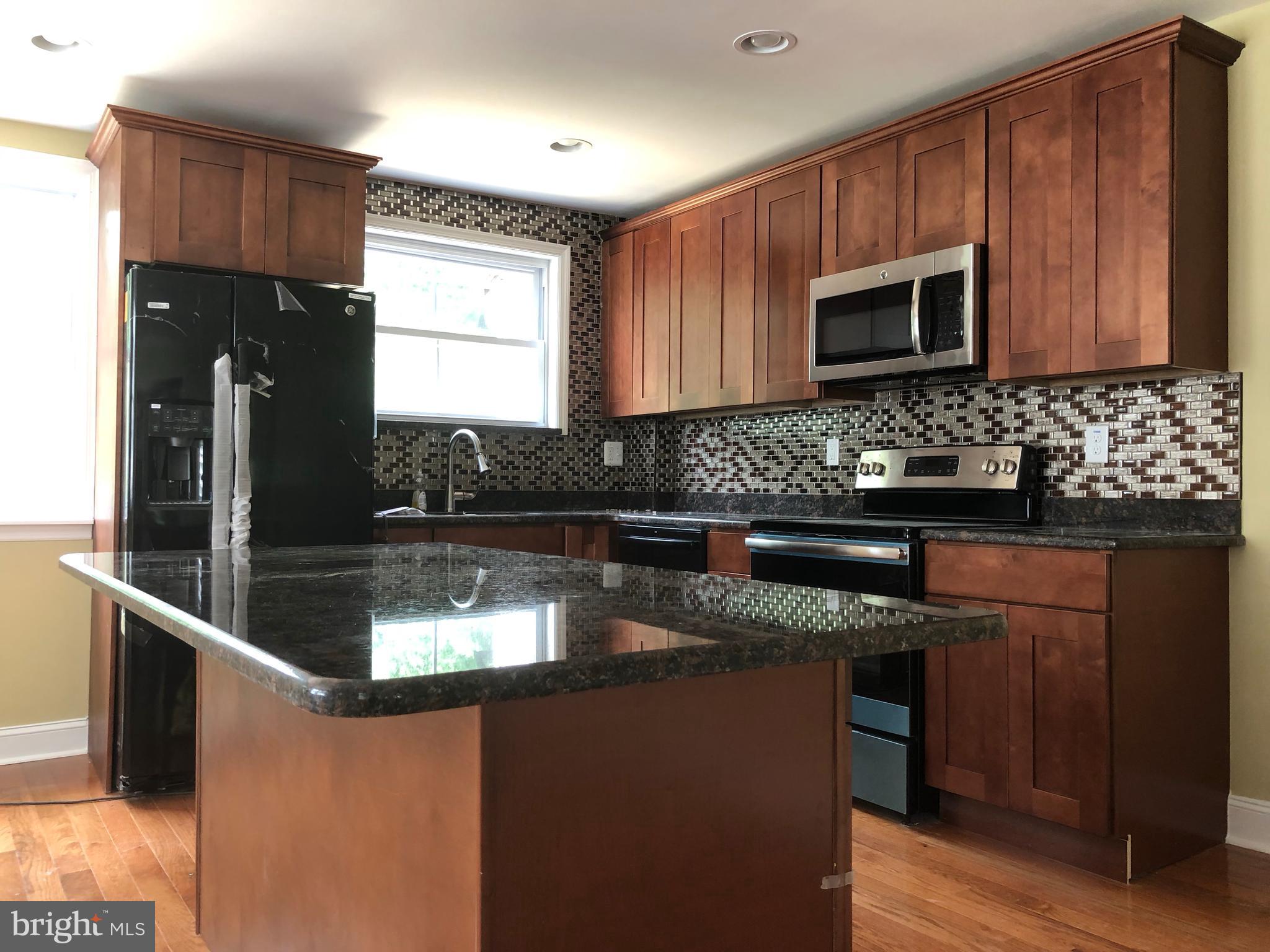 7703 Parkview Road Upper Darby, PA 19082 - Photo 7 of 30 a kitchen with stainless steel appliances granite countertop a sink a stove a microwave a refrigerator and cabinets