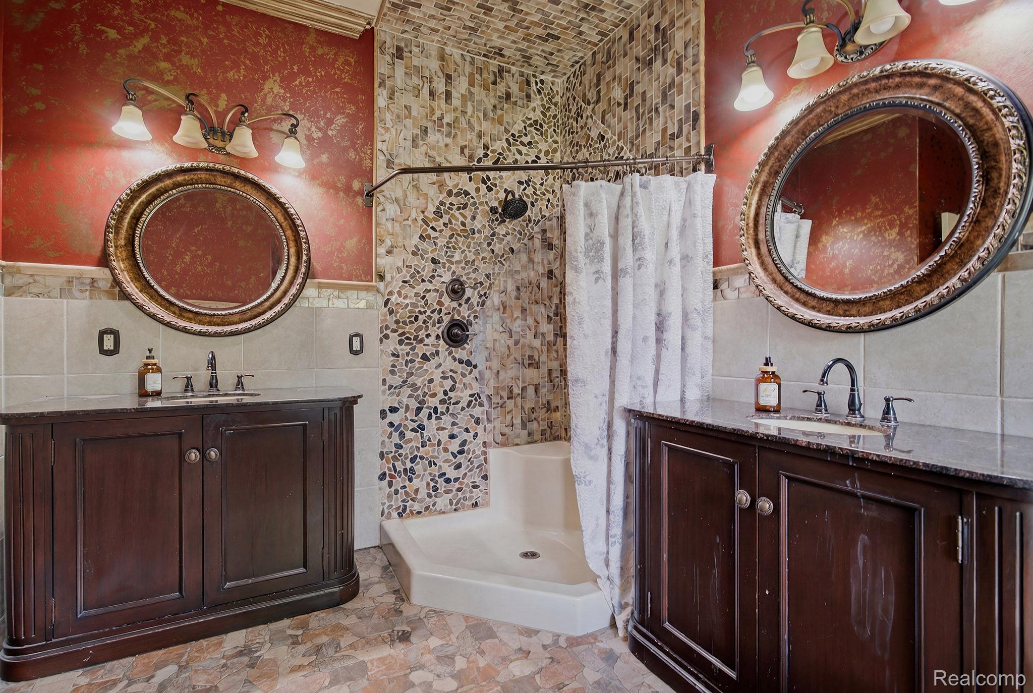 1258 Priscilla Lane Rochester, MI 48309 - Photo 50 of 56 Dual dark wood vanities with integrated sinks, each featuring an ornate framed mirror and a three-light fixture