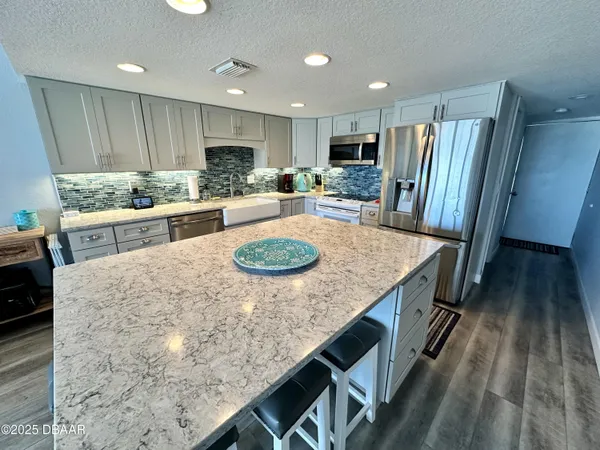a kitchen with stainless steel appliances granite countertop a kitchen island hardwood floor sink and stove