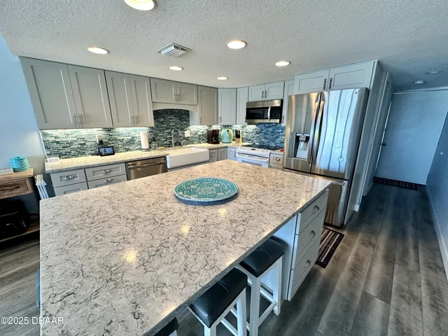 a kitchen with stainless steel appliances granite countertop a kitchen island hardwood floor sink and stove