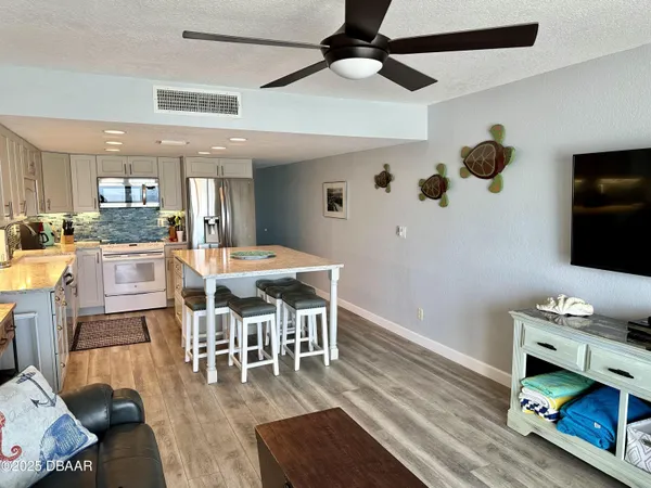 a dining room with wooden floor a chandelier fan a wooden table and chairs