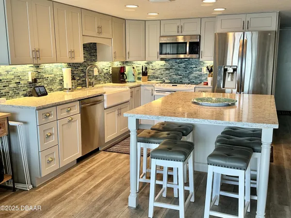 a kitchen with stainless steel appliances kitchen island granite countertop a table chairs sink and cabinets