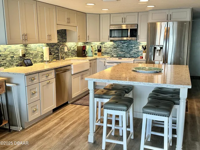 a kitchen with stainless steel appliances kitchen island granite countertop a table chairs sink and cabinets
