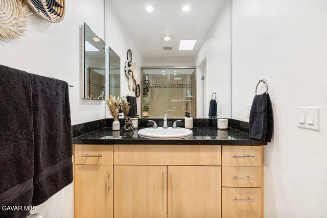a bathroom with a granite countertop sink and a mirror