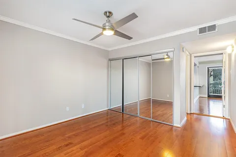 an empty room with wooden floor and a ceiling fan