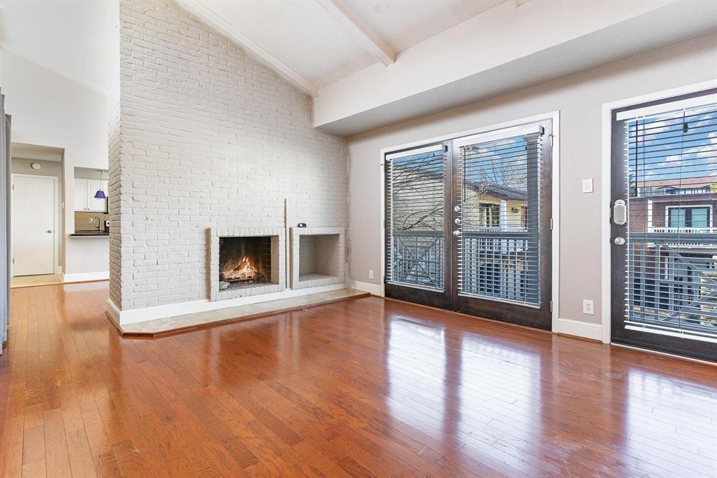 5934 Sandhurst Lane, Unit 207 Dallas, TX 75206 - Photo 2 of 31 Unfurnished living room featuring hardwood / wood-style flooring, a fireplace, beam ceiling, and high vaulted ceiling