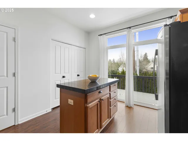 a kitchen with stainless steel appliances granite countertop a stove a refrigerator and a view of living room