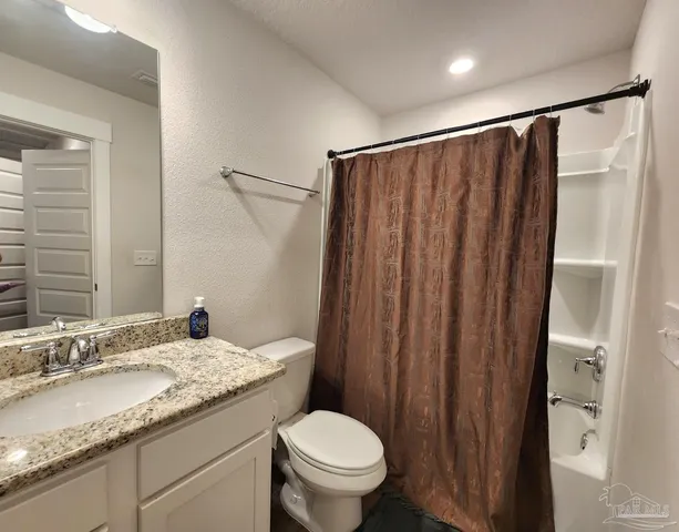 a bathroom with a granite countertop sink toilet and a mirror