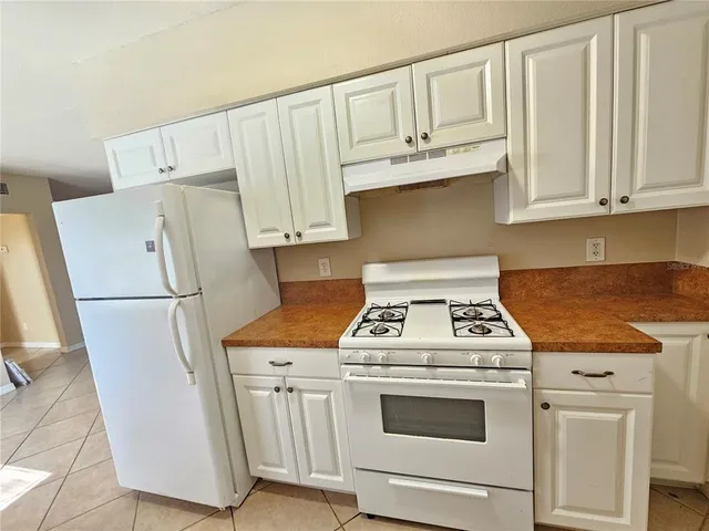 a kitchen with granite countertop white cabinets and white appliances