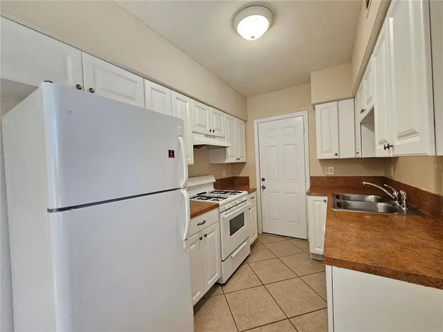 a kitchen with stainless steel appliances granite countertop a refrigerator a stove a sink and white cabinets