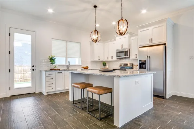 a kitchen with white cabinets stainless steel appliances and wooden floor
