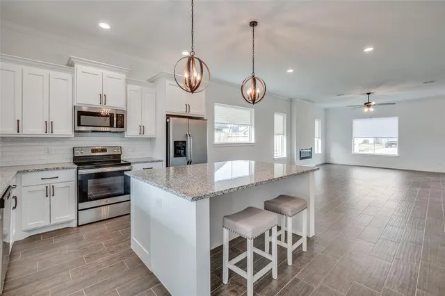 a kitchen with stainless steel appliances kitchen island granite countertop a stove a sink and a wooden floors